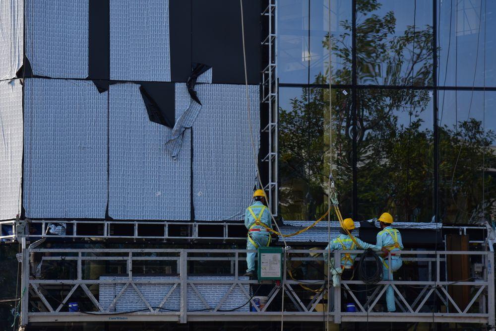 Bouwprofessionals werken vanaf een steiger aan een gevel