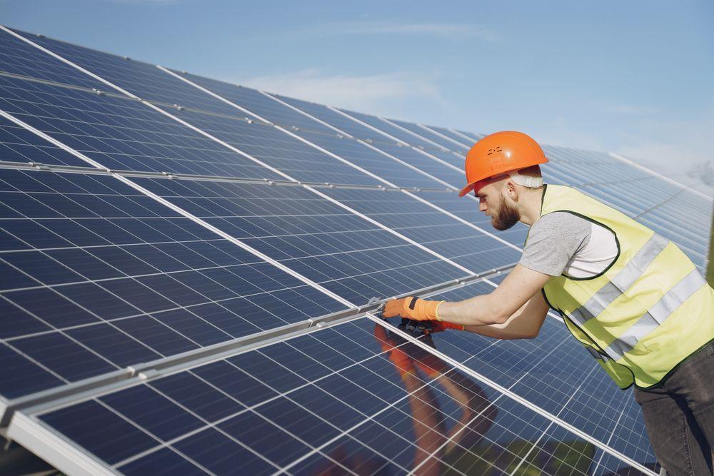 Technicus met helm en handschoenen installeert zonnepanelen