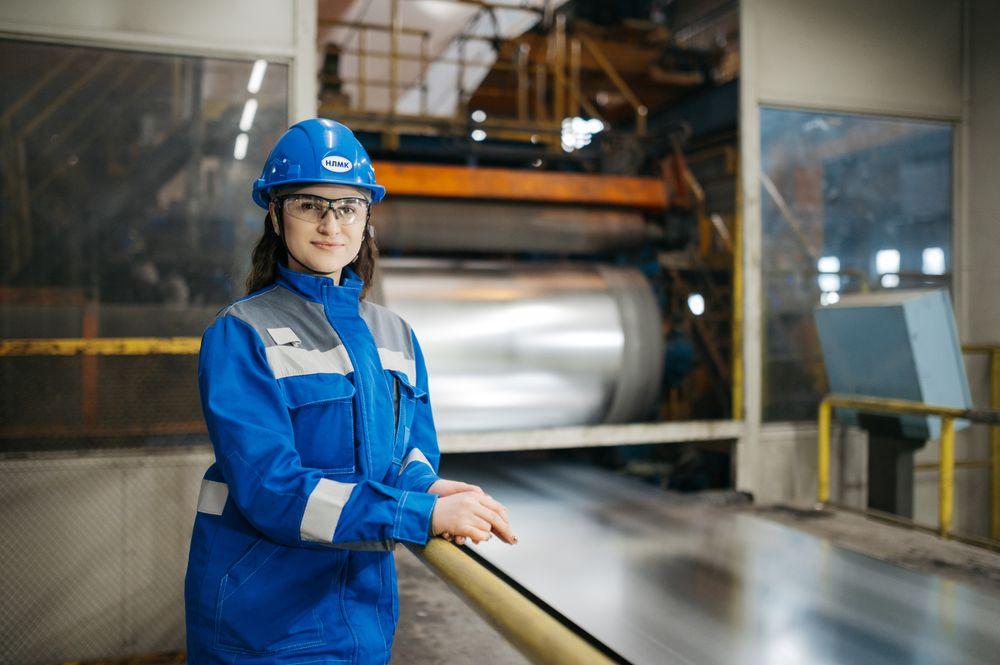 Medewerker in blauwe veiligheidskleding in een industriële productiehal
